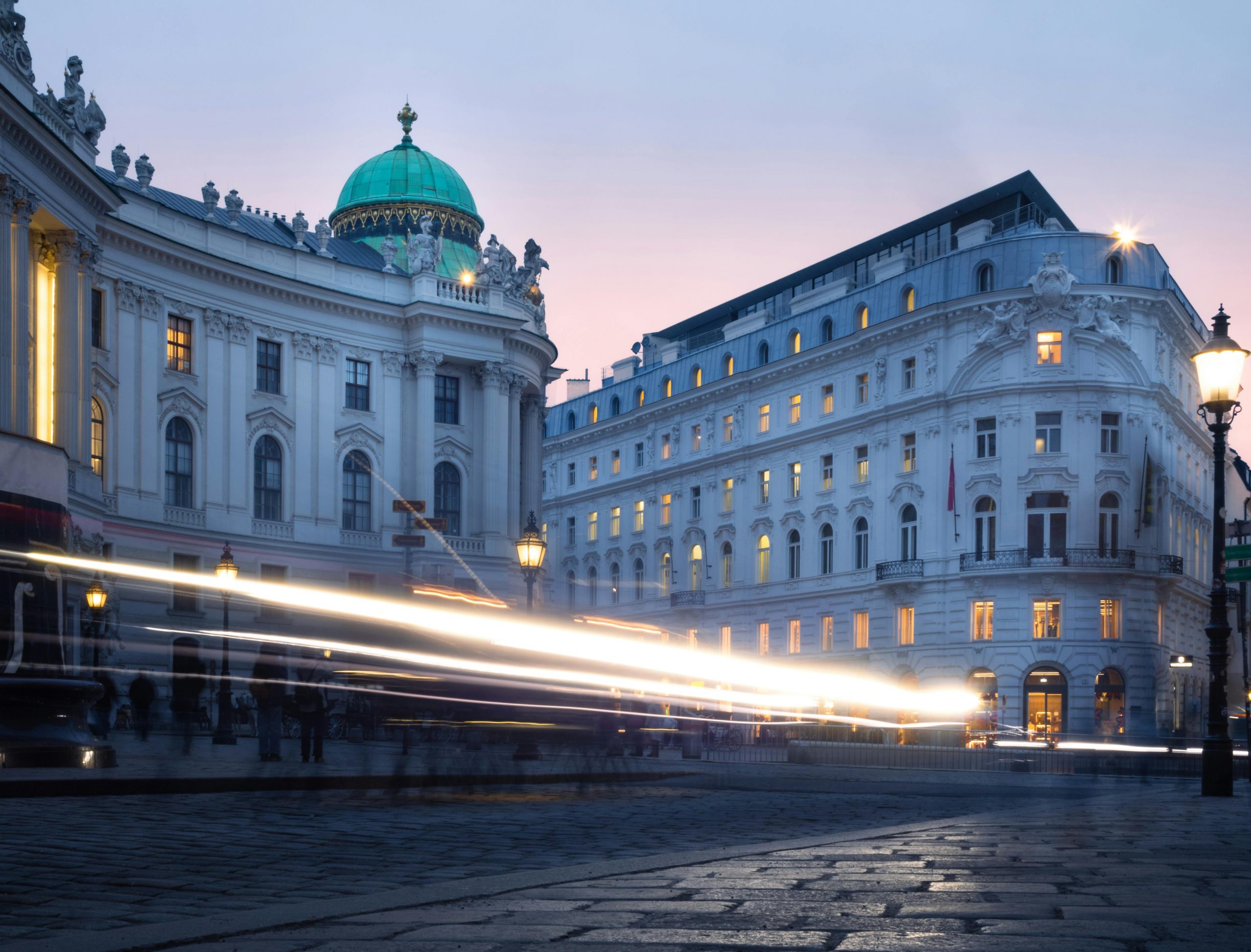 A stunning view of Vienna's Hofburg Palace at twilight with light trails creating a dynamic urban scene.