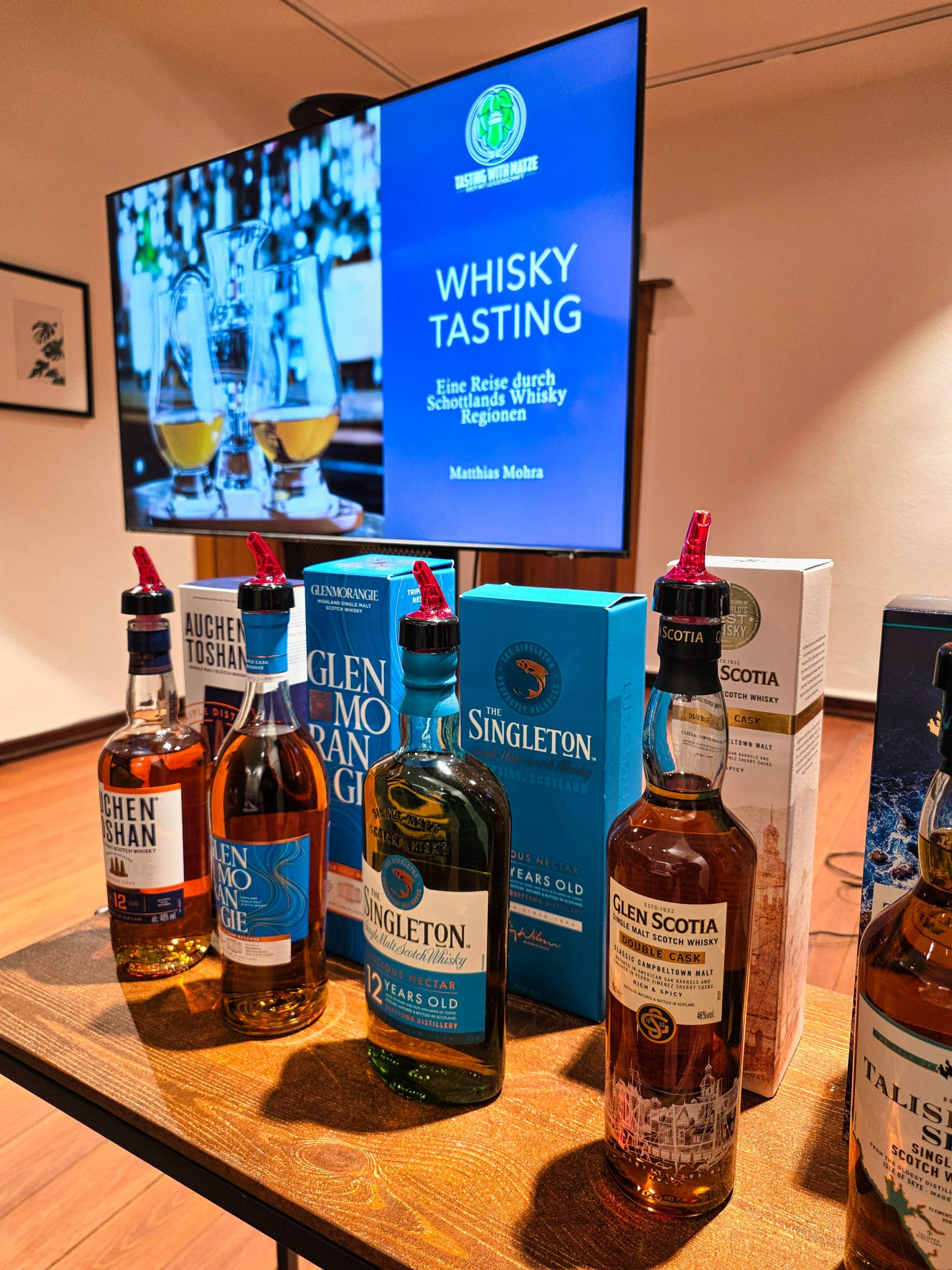 Auswahl an Whiskyflaschen und Präsentation auf dem TV beim Tasting
