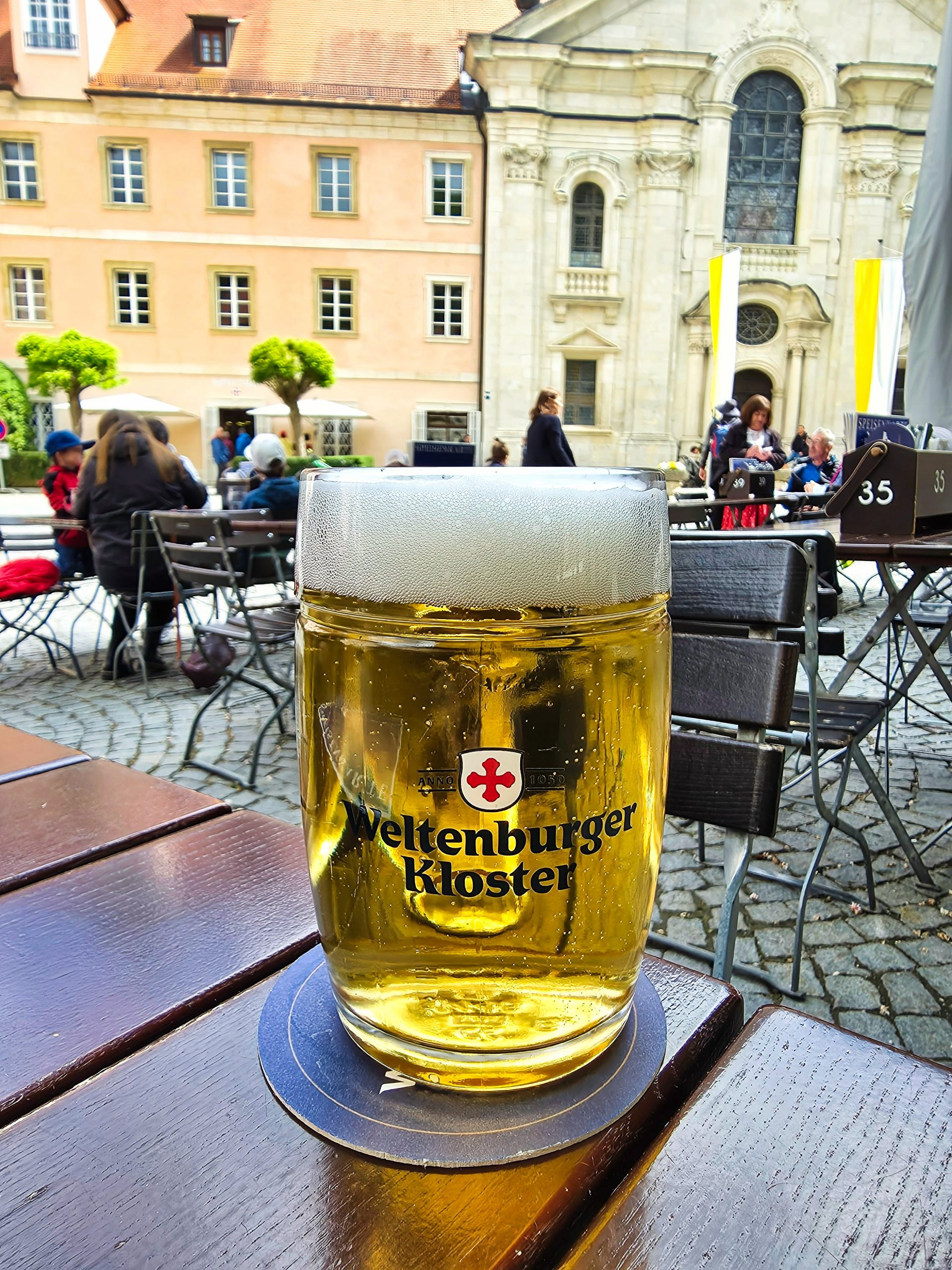 Frisch gezapftes Weltenburger Bier im schattigen Biergarten des Klosterhofs